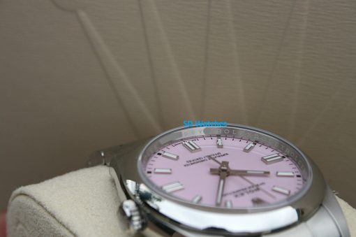 IMG_7111 | SD Watches Close-up of a pink Rolex wristwatch with a silver bezel, resting on a beige glove-like surface; visible hour markers and hands dominate the dial.