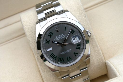 IMG_7133 | SD Watches Close-up of a stainless steel Rolex Oyster Perpetual Datejust wristwatch with a gray dial and green Roman numerals on a beige cushion.