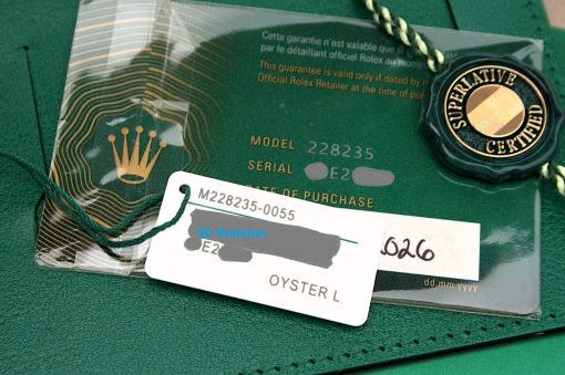 IMG_7152 | SD Watches Close-up of a green Rolex tag and certificate showing model 228235 and a Superlative Certified seal on a green surface.