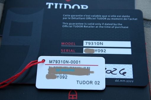 IMG_7199 | SD Watches Close-up of Tudor watch tags showing model 79310N and serial ending in Y092, attached with a red cord on a dark surface232.
