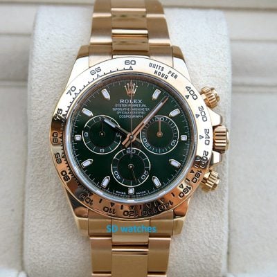 Gold Rolex Daytona chronograph with a green dial and tachymeter bezel on a beige display cushion
