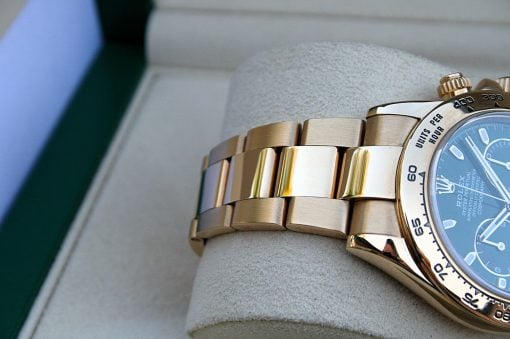 IMG_7210 | SD Watches Close-up of a gold Rolex watch band with a blue dial and rotating bezel, resting on a soft surface.
