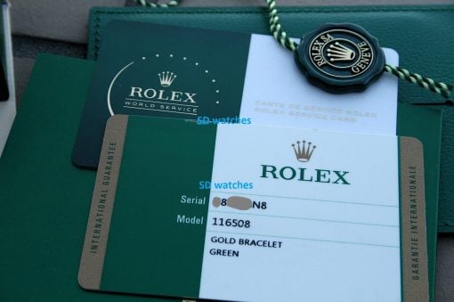 IMG_7218 | SD Watches Close-up of Rolex watch documentation: green service card, white Rolex card, and a dark seal with the Rolex crown logo on a green leather case.