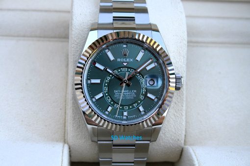 IMG_7244 | SD Watches Close-up of a Rolex Sky-Dweller stainless steel watch with a green dial and fluted bezel on a beige display cushion.