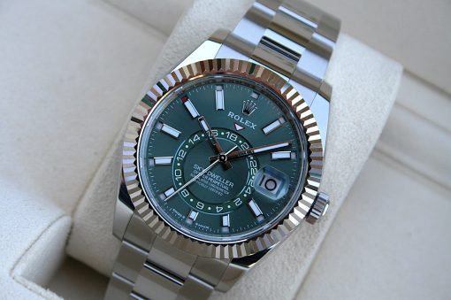 IMG_7245 | SD Watches Close-up of a Rolex watch with a green dial, fluted bezel, and metal bracelet resting on a beige cushion.