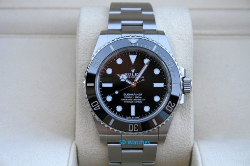 Rolex 124060 | SD Watches Close-up of a stainless steel Rolex Submariner watch on a beige display cushion, featuring a black dial and silver bezel edge accessibly visible in front of the camera.