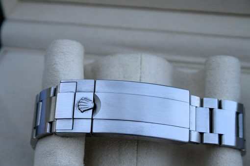 IMG_7251 | SD Watches Close-up of a silver Rolex watch bracelet with the crown logo on the clasp, wrapped around a beige pillar or support.