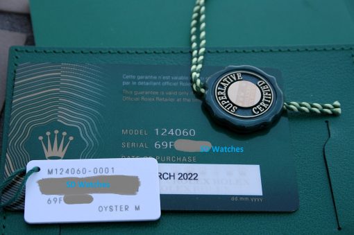 IMG_7254 | SD Watches Rolex warranty card with official seal and braided cord on a green background; model 124060, serial partially visible.