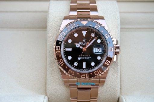 Rolex 126715 | SD Watches Rose gold Rolex GMT-Master II wristwatch on a beige display cushion, showing a black dial and date window at 3 o'clock.