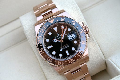IMG_7276 | SD Watches Rose gold Rolex GMT-Master II wristwatch with black dial, date window, and a blue-bezel, resting on a light beige display cushion.