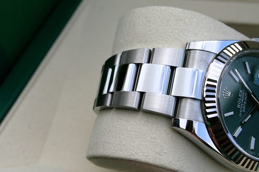 IMG_7288 | SD Watches Close-up of a stainless steel Rolex watch bracelet and fluted bezel resting on a light beige cushion.