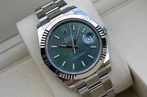 IMG_7295 | SD Watches Close-up of a Rolex Datejust wristwatch with a green dial, magnified date window at 3 o'clock showing 10, and a polished stainless steel bracelet.