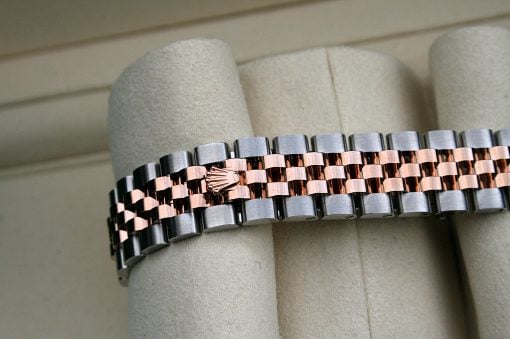 IMG_7305 | SD Watches Close-up of a two-tone watch bracelet with rose gold center links and silver outer links on a padded display surface.