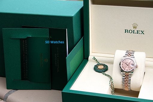 IMG_7311 | SD Watches Open green Rolex presentation box displaying a two-tone Rolex watch with pink dial and beige interior, plus warranty cards nearby.