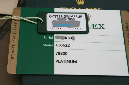 IMG_7329 | SD Watches Green ROLEX warranty card with a hanging white tag that reads OYSTER SWIMPRUF and shows blurred serial/model numbers, attached by a rope looped through a hole.