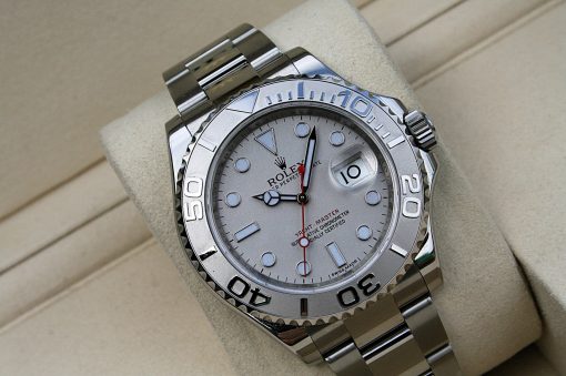 IMG_7331 | SD Watches Close-up of a silver Rolex Yacht-Master wristwatch on a beige cushion, showing the dial and rotating bezel with bold numerals.