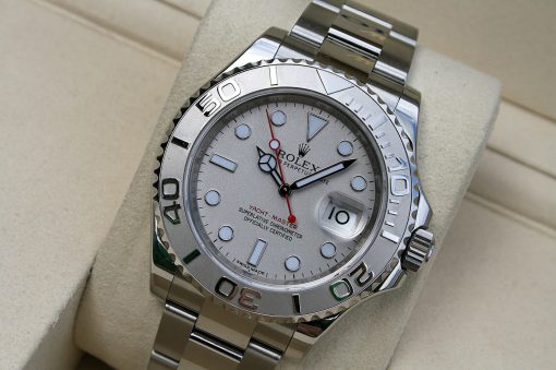 IMG_7336 | SD Watches Close-up of a silver Rolex Yacht-Master watch on a beige cushion, displaying the bezel, dial, and date window at 3 o'clock.