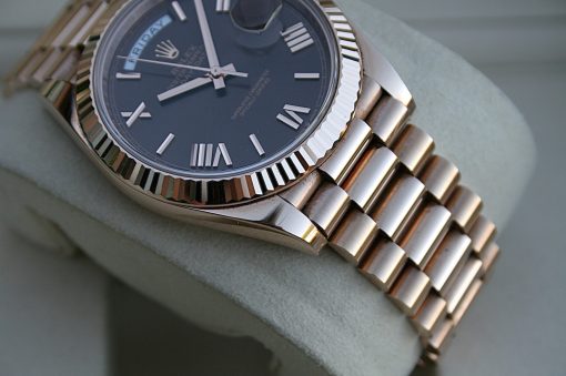 IMG_7357 | SD Watches Close-up of a Rolex wristwatch with a dark blue dial, Roman numeral markers, and a fluted silver bezel resting on a soft cushion.