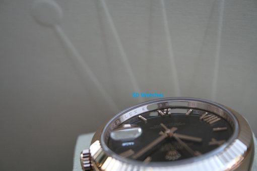 IMG_7360 | SD Watches Close-up of a luxury Rolex watch partially visible at the bottom right, showing a metal bezel and black dial.