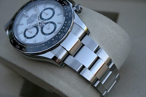 IMG_7375 | SD Watches Close-up of a silver chronograph wristwatch with a white dial, black tachymeter bezel, and metal bracelet on a beige cushion.
