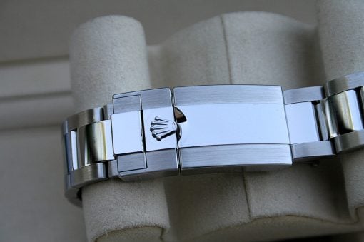 IMG_7377 | SD Watches Close-up of a silver Rolex watch bracelet with the crown logo on the clasp, resting on a soft gray cushion?