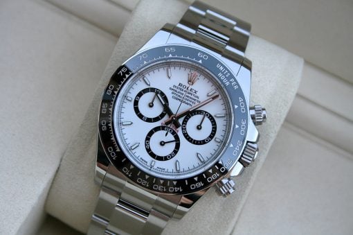 IMG_7387 | SD Watches Close-up of a stainless steel Rolex Daytona watch with a white dial, black subdials, and tachymeter bezel on a beige cushion.