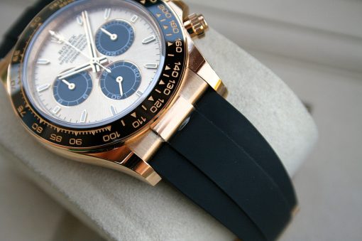 IMG_7391 | SD Watches Close-up of a luxury wristwatch with a gold case, white dial, blue subdials, and a black strap on a soft surface.