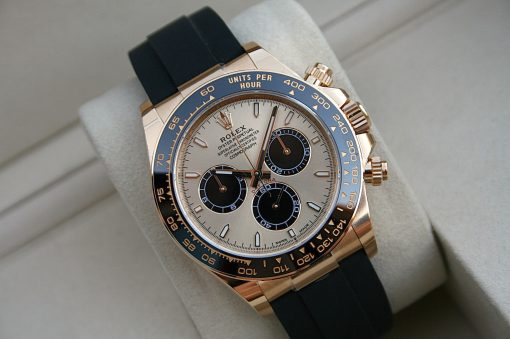 IMG_7402 | SD Watches Close-up of a gold Rolex Daytona watch with a blue bezel and black rubber strap on a cushioned display surface
