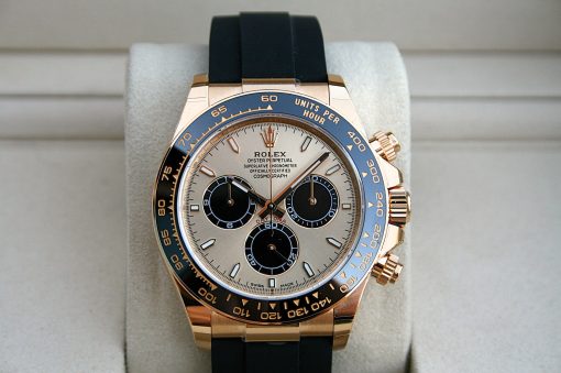 IMG_7403 | SD Watches Gold Rolex Daytona watch with a blue tachymeter bezel and black strap resting on a light display cushion.