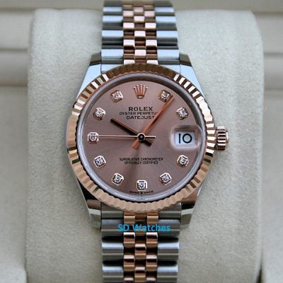 Two-tone Rolex Datejust wristwatch with diamond hour markers on a pink dial, displayed on a beige cushion.