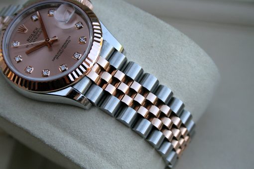 IMG_7412 | SD Watches Close-up of a two-tone Rolex watch with a pink dial, diamond hour markers, and a fluted bezel on a soft surface