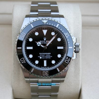 Rolex 124060 | SD Watches Rolex Submariner watch with black dial, silver bezel, and stainless steel bracelet on a beige cushion.