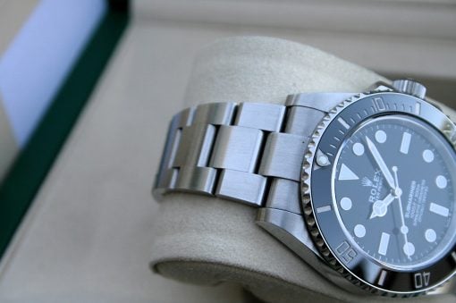 IMG_7435 | SD Watches Close-up of a silver Rolex diver's watch with a metal bracelet on a beige surface, showing the bezel and dial edge.