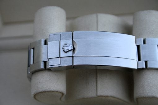 IMG_7436 | SD Watches Close-up of a silver metal watch bracelet clasp with the Rolex crown emblem, on a light background.