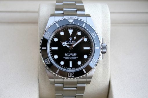 IMG_7443 | SD Watches Close-up of a stainless steel Rolex Submariner watch resting on a beige display cushion, showing its black dial and bezel.
