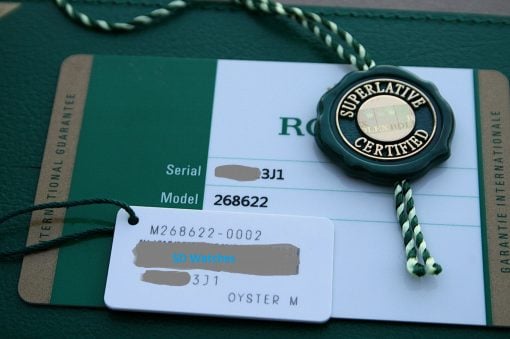 IMG_7458 | SD Watches Green Rolex warranty card with a teal 'Superlative Certified' seal resting on it.