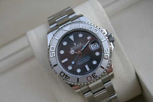 IMG_7461 | SD Watches Close-up of a silver Rolex Yacht-Master watch with a dark dial and rotating bezel, resting on a beige cushion.