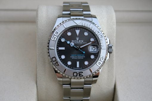 IMG_7462 | SD Watches Close-up of a silver Rolex Yacht-Master watch with black dial, date window, and blue accents on a beige cushion.
