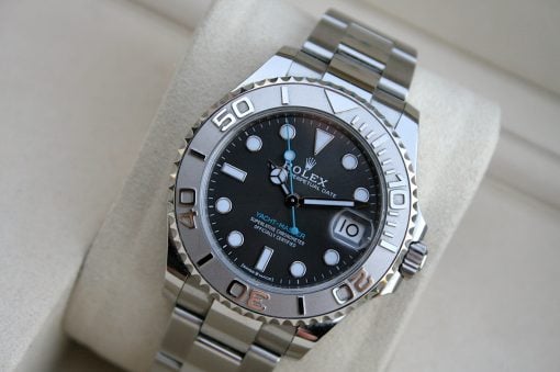 IMG_7465 | SD Watches Close-up of a stainless steel Rolex Yacht-Master watch on a beige cushion, featuring a black dial and a silver rotating bezel with large numerals.