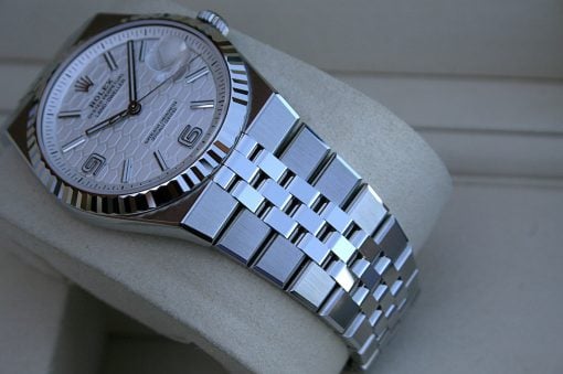 IMG_7489 | SD Watches Close-up of a silver Rolex Oyster Perpetual watch with a patterned white dial and stainless steel bracelet on a light cushion.