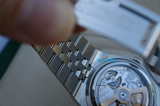 IMG_7492 | SD Watches Close-up of a mechanical watch movement showing brushed metal links and gears with a blue 'SD Watches' watermark.