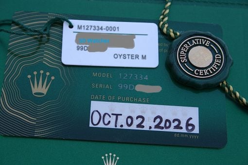 IMG_7493 | SD Watches Close-up of a Rolex warranty card with a white tag labeled 'SD Watches' placed over the card, and a circular 'Superlative Certified' seal nearby.