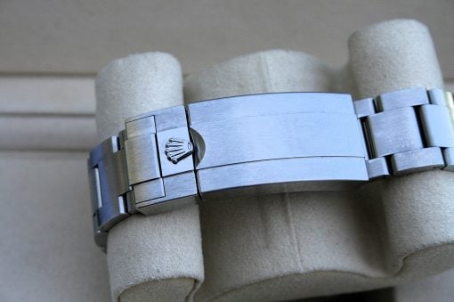 IMG_7508 | SD Watches Close-up of a stainless steel Rolex watch band resting on a cushioned display, featuring the Rolex crown logo on the clasp.