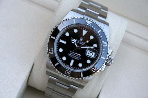 IMG_7519 | SD Watches Close-up of a stainless steel Rolex Submariner wristwatch with a black dial, rotating bezel, and date window magnified at 3 o'clock on a light surface.